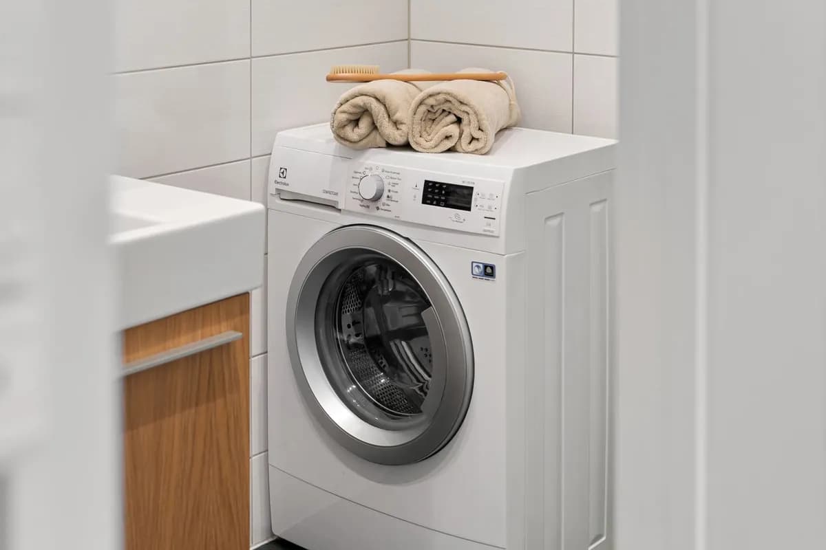 White front-loading washing machine in a bright laundry corner
