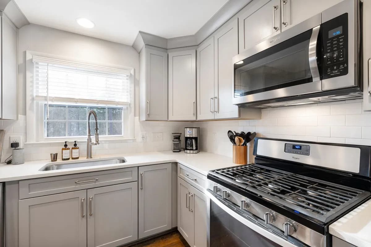 Stainless steel kitchen appliances in a bright white kitchen